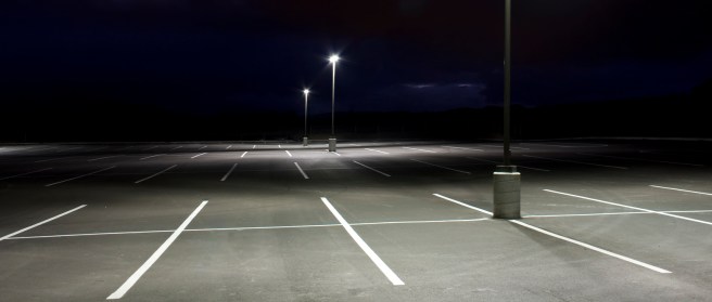 Empty parking lot at night with white lines and two light posts